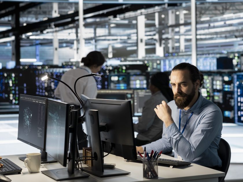 Technician using PC in data center to update server tech, configuring equipment using software tools. Server room employee reviewing hardware analytics, ensuring reliable network operations